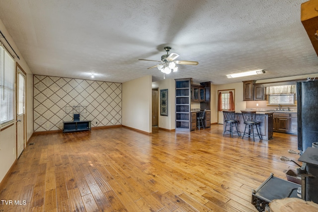 unfurnished living room featuring a wealth of natural light, light hardwood / wood-style floors, and a textured ceiling