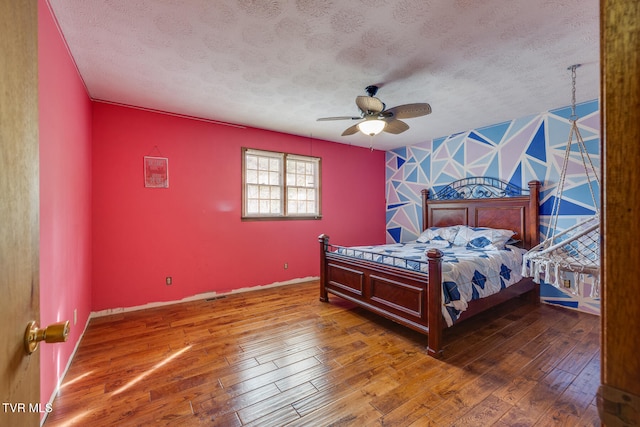 bedroom featuring dark hardwood / wood-style flooring, a textured ceiling, and ceiling fan