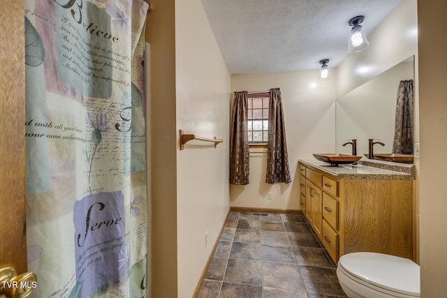 bathroom with vanity, a textured ceiling, and toilet