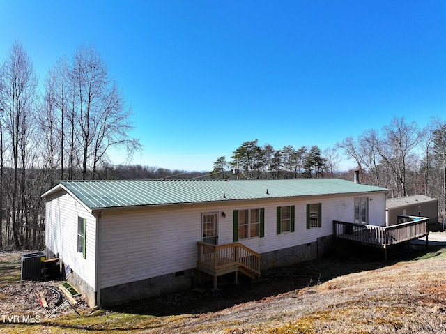 back of house featuring crawl space, central AC, metal roof, and a deck