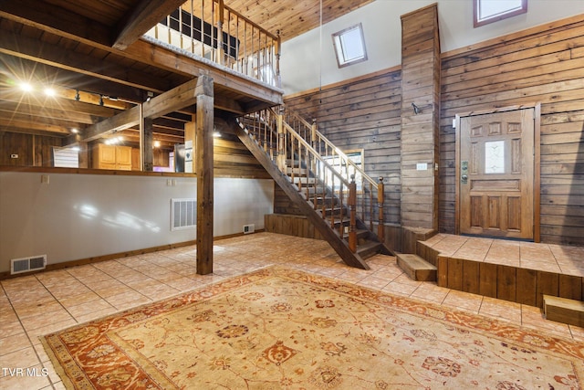 entryway with wood walls, tile patterned floors, a high ceiling, and wood ceiling