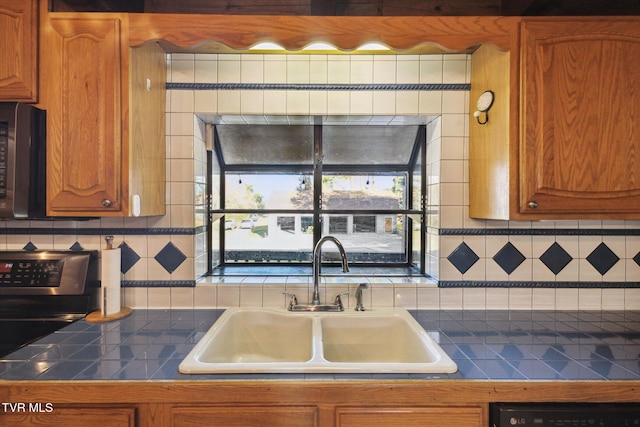 kitchen featuring black appliances, sink, and tasteful backsplash