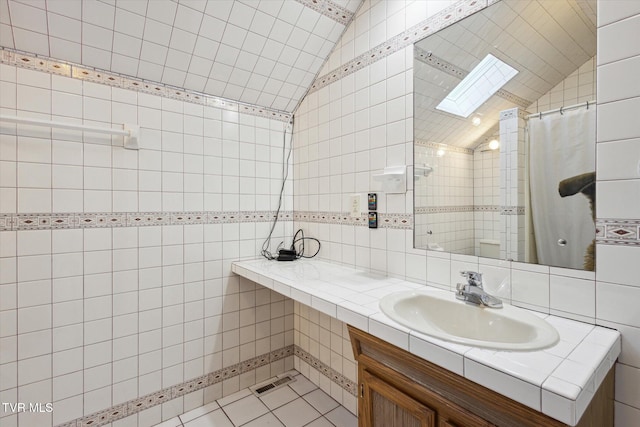 bathroom featuring tile walls, vanity, tile patterned flooring, curtained shower, and lofted ceiling with skylight