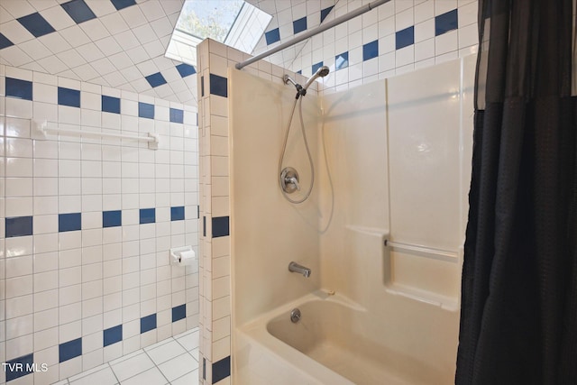 bathroom with tile walls, tile patterned flooring, a skylight, and shower / bath combination with curtain