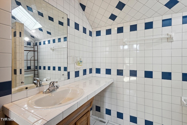 bathroom with a skylight, vanity, and tile walls