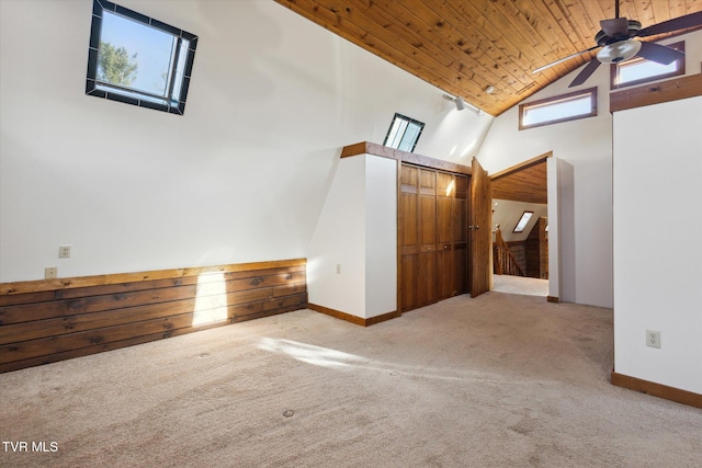 spare room with high vaulted ceiling, wood ceiling, light colored carpet, and ceiling fan