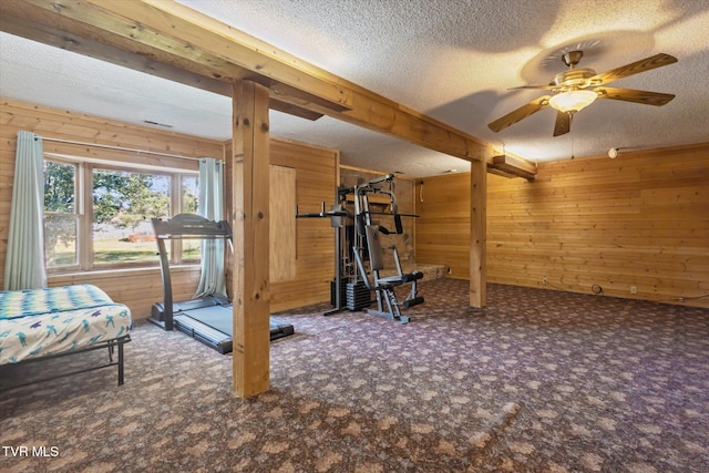 workout room featuring wood walls, ceiling fan, a textured ceiling, and carpet floors