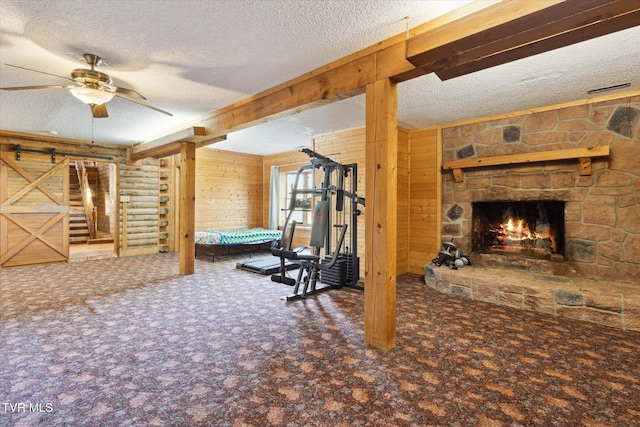 interior space with ceiling fan, a textured ceiling, carpet flooring, a fireplace, and a barn door