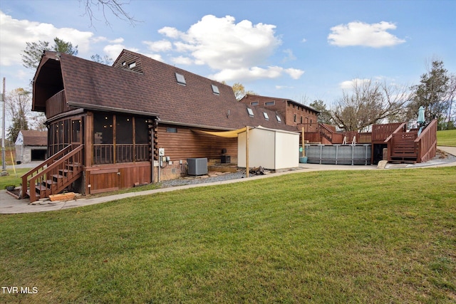 back of house featuring central air condition unit, a sunroom, and a yard