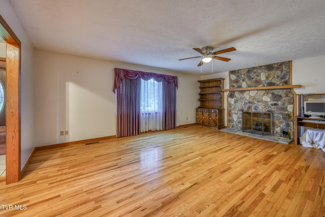 unfurnished living room featuring a textured ceiling, a fireplace, light hardwood / wood-style flooring, and ceiling fan