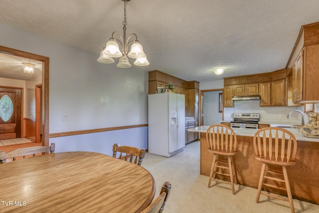 kitchen featuring sink, a textured ceiling, stainless steel range with electric stovetop, an inviting chandelier, and white fridge with ice dispenser