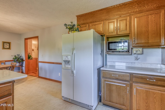 kitchen featuring a textured ceiling and white refrigerator with ice dispenser