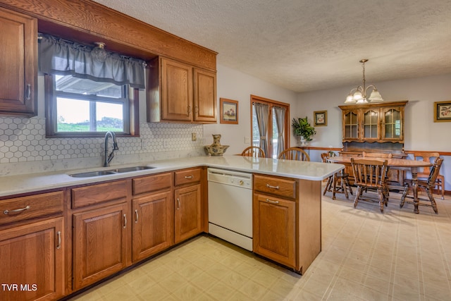 kitchen featuring dishwasher, kitchen peninsula, sink, tasteful backsplash, and pendant lighting