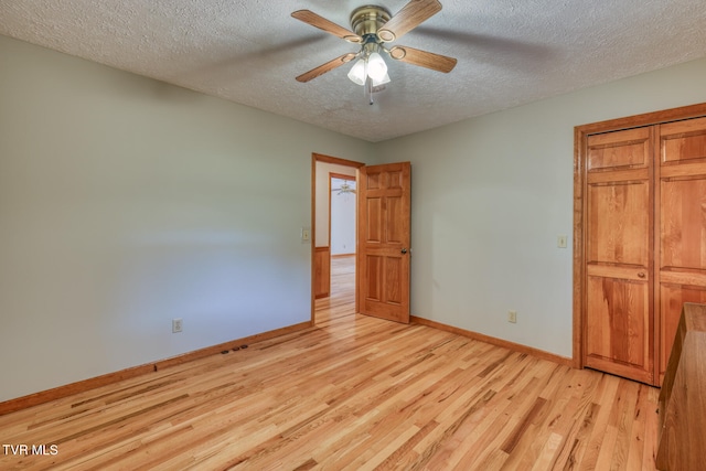 unfurnished bedroom featuring a closet, light wood-type flooring, a textured ceiling, and ceiling fan