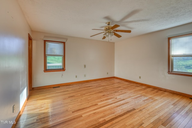 spare room with ceiling fan, a textured ceiling, and light wood-type flooring