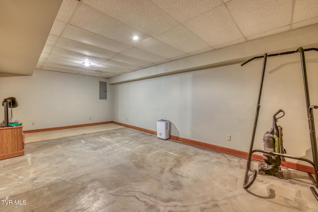 basement featuring a paneled ceiling and electric panel