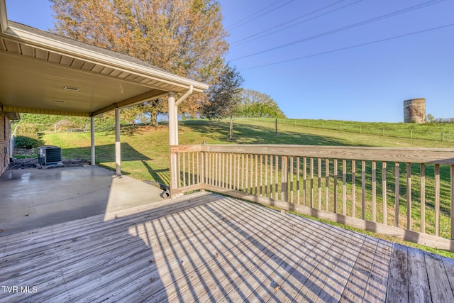 wooden terrace featuring central AC unit, a rural view, a yard, and a patio area