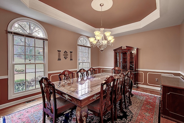 dining space with a wealth of natural light, an inviting chandelier, and a raised ceiling