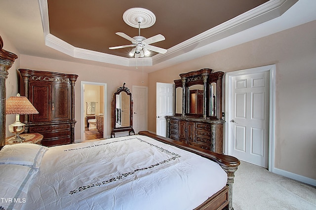 bedroom featuring connected bathroom, carpet, ceiling fan, ornamental molding, and a tray ceiling