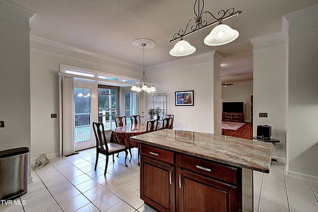 kitchen featuring decorative light fixtures, a center island, ornamental molding, ceiling fan with notable chandelier, and a breakfast bar