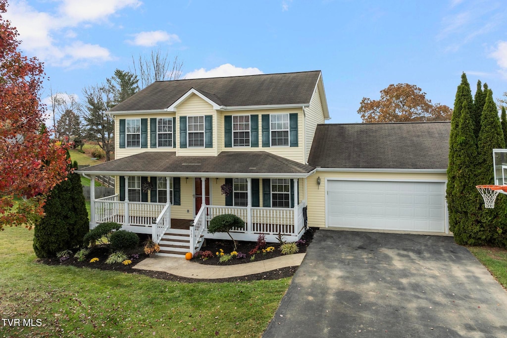 colonial-style house featuring a front lawn, covered porch, and a garage