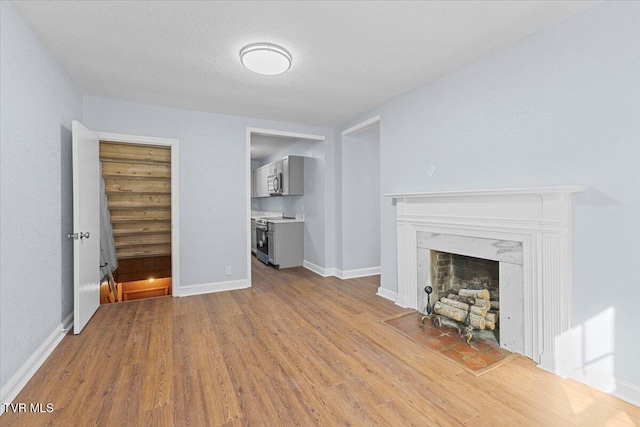 unfurnished living room featuring light wood-type flooring, a fireplace, and a textured ceiling