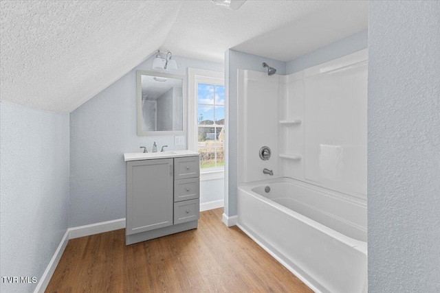 bathroom with lofted ceiling, a textured ceiling, hardwood / wood-style flooring, vanity, and shower / tub combination