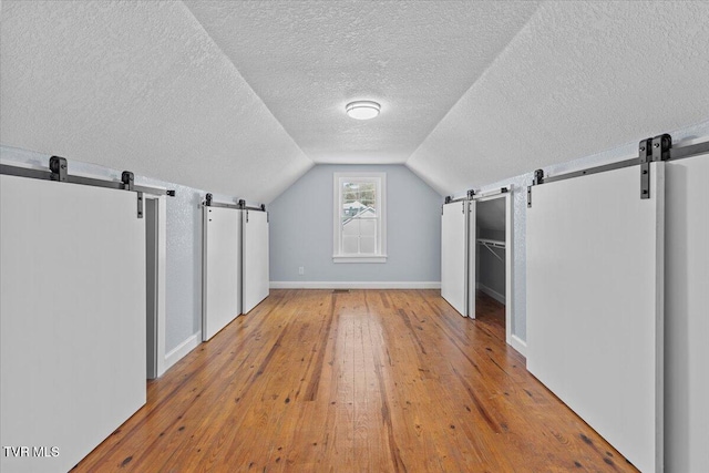 bonus room with light wood-type flooring, vaulted ceiling, and a textured ceiling