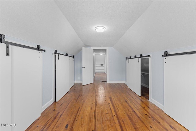 bonus room with wood-type flooring, a textured ceiling, and vaulted ceiling