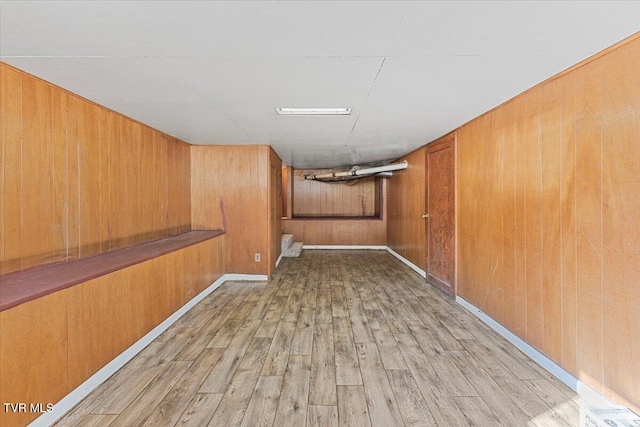 basement with light hardwood / wood-style floors and wood walls