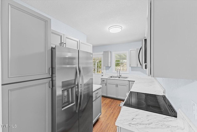 kitchen featuring light hardwood / wood-style floors, sink, appliances with stainless steel finishes, a textured ceiling, and gray cabinets