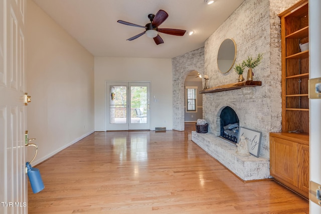 unfurnished living room featuring light wood-type flooring, a large fireplace, and ceiling fan