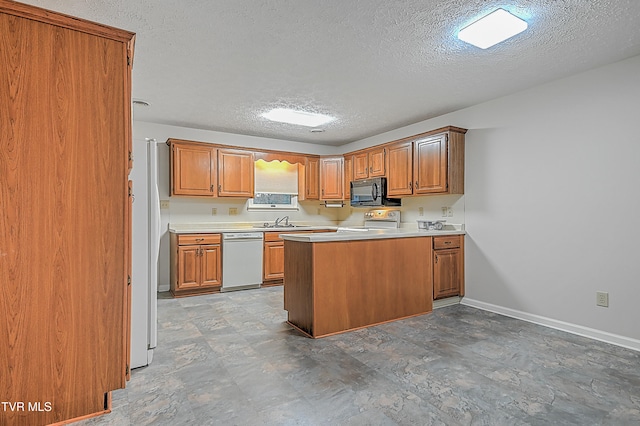 kitchen featuring white appliances, a textured ceiling, sink, and kitchen peninsula