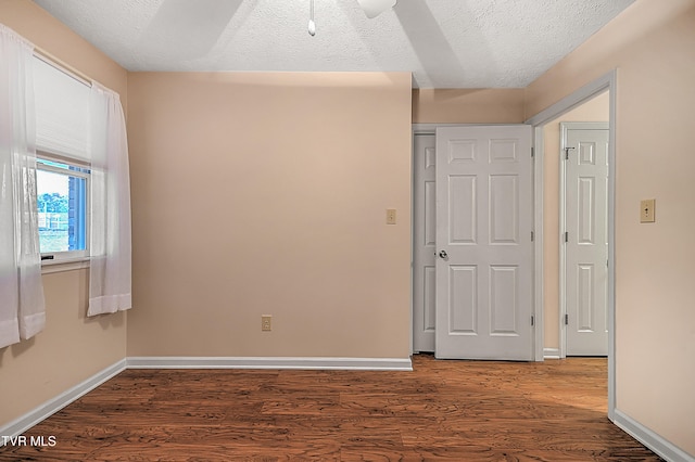 unfurnished room with dark wood-type flooring and a textured ceiling