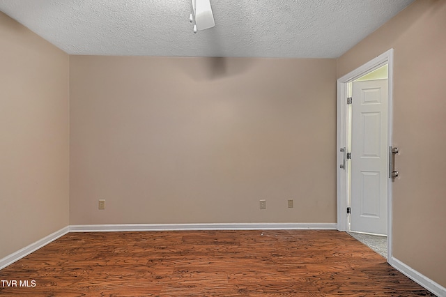 empty room featuring a textured ceiling and dark hardwood / wood-style floors