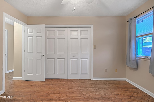 unfurnished bedroom featuring a textured ceiling, wood-type flooring, and ceiling fan