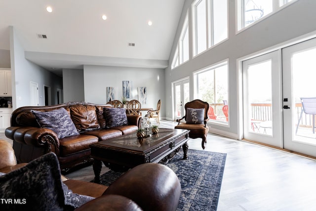 living room featuring light wood-type flooring, high vaulted ceiling, and french doors