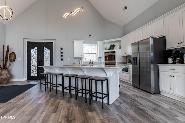 kitchen with a center island, stainless steel appliances, white cabinetry, and hanging light fixtures