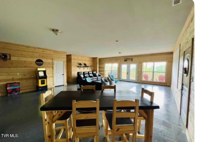 dining space with wood walls and french doors