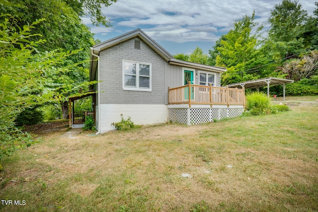 rear view of house featuring a yard, a carport, and a wooden deck