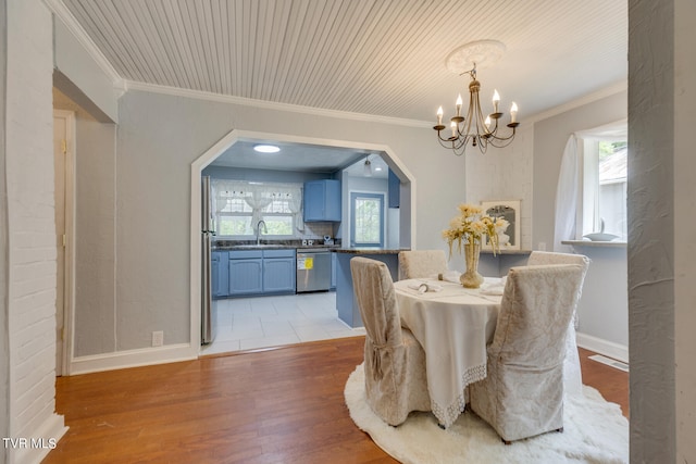 dining area featuring ornamental molding, light wood-type flooring, and sink