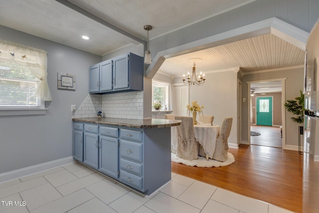 kitchen with ornamental molding, kitchen peninsula, decorative backsplash, and light wood-type flooring