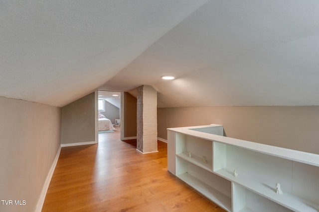 additional living space with lofted ceiling and light hardwood / wood-style flooring