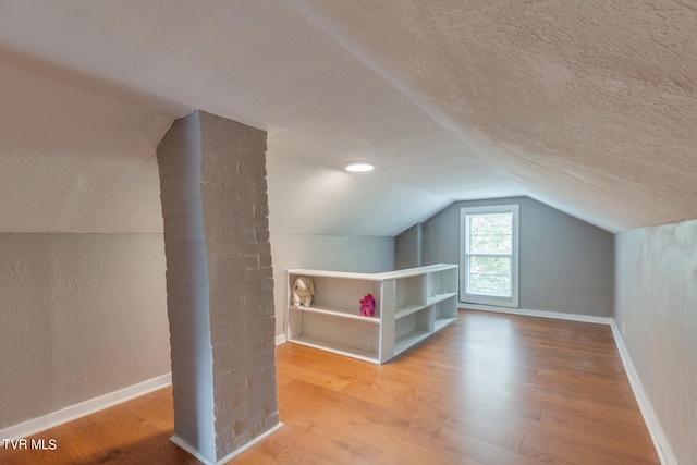 bonus room with hardwood / wood-style flooring, a textured ceiling, and lofted ceiling