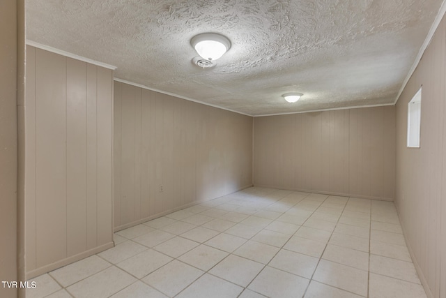 spare room with a textured ceiling, light tile patterned floors, and wooden walls