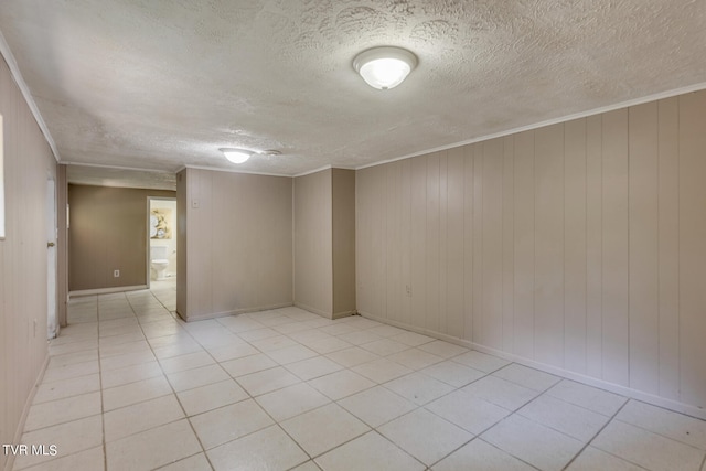 tiled spare room with a textured ceiling, wooden walls, and crown molding