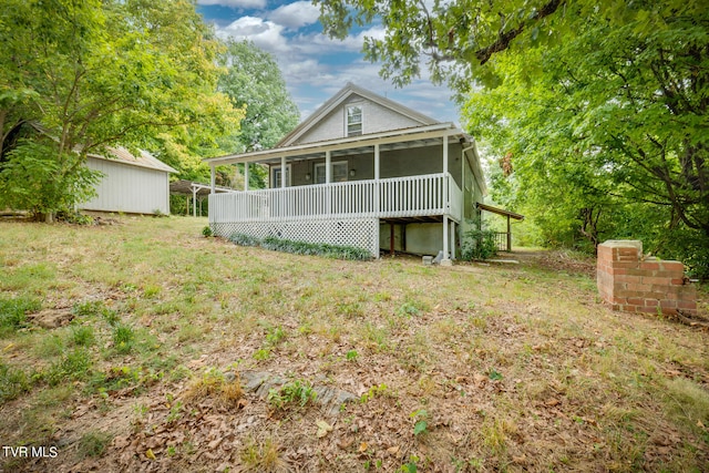 rear view of house featuring a lawn and a sunroom