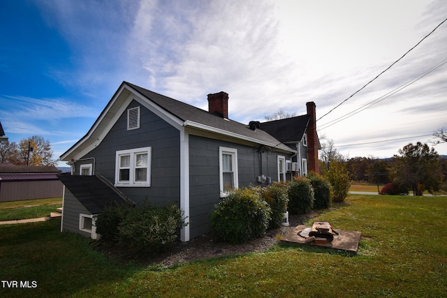 view of side of property with a yard and a fire pit