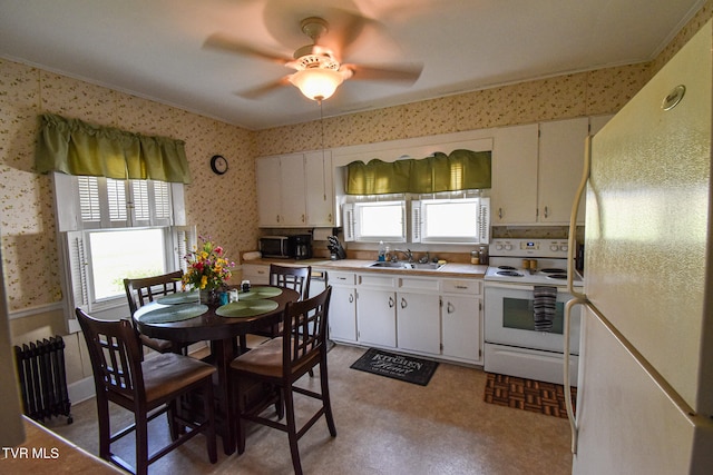 kitchen with radiator, plenty of natural light, sink, white cabinetry, and white appliances