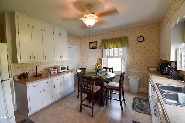 kitchen featuring white cabinets, sink, white appliances, and ceiling fan